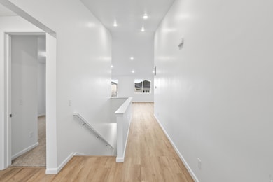 Hall featuring an upstairs landing, light wood finished floors, and recessed lighting