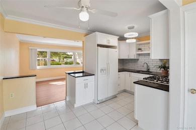 Kitchen with light tile patterned flooring, ornamental molding, tasteful backsplash, white appliances, and open shelves
