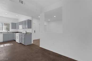 Kitchen featuring white appliances, gray cabinetry, and recessed lighting