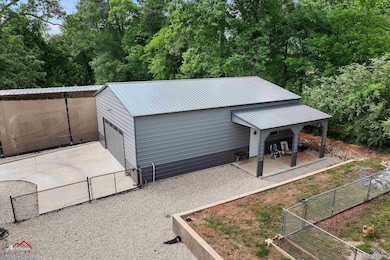 Exterior space featuring a gate, driveway, fence, a garage, and an outdoor structure