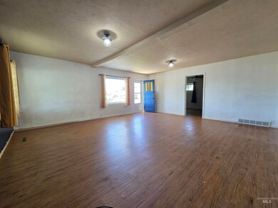 Unfurnished room featuring wood finished floors, a textured ceiling, and beam ceiling