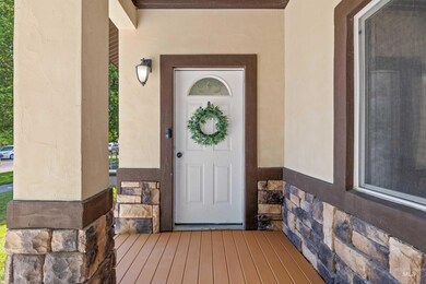 Entrance to property featuring stone siding, stucco siding, and a porch