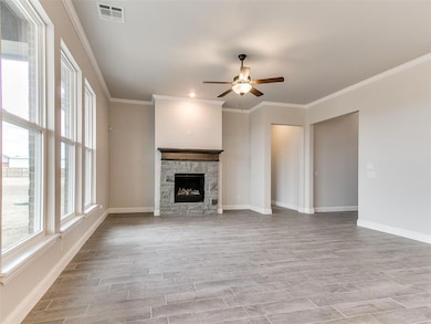Unfurnished living room with wood tiled floors, ornamental molding, ceiling fan, and a fireplace