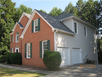 View of home's exterior with concrete driveway, brick siding, a shingled roof, and a garage