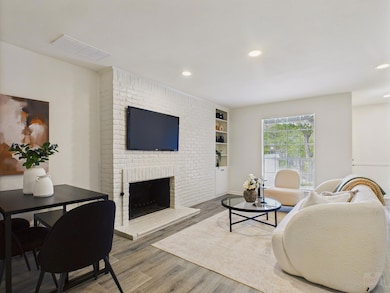 Living room featuring a brick fireplace, wood finished floors, recessed lighting, and built in shelves