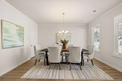 Dining space with crown molding, wood finished floors, and a chandelier