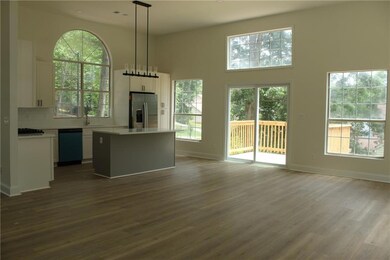 Unfurnished living room featuring dark wood-type flooring, a high ceiling, baseboards, and a sink