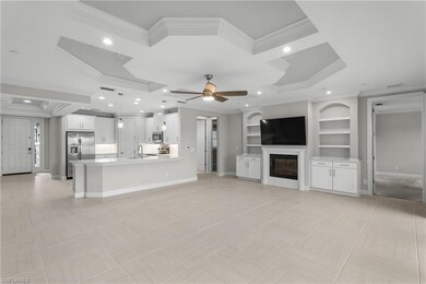 Unfurnished living room featuring crown molding, a sink, coffered ceiling, a glass covered fireplace, and a ceiling fan