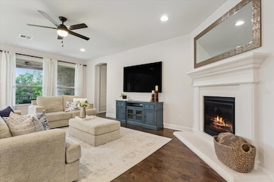 Living area featuring dark wood-type flooring, recessed lighting, arched walkways, a glass covered fireplace, and a ceiling fan