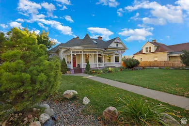 Victorian house featuring covered porch, a front yard, and a chimney