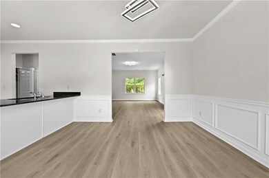 Unfurnished living room featuring ornamental molding, a wainscoted wall, and light wood-style flooring
