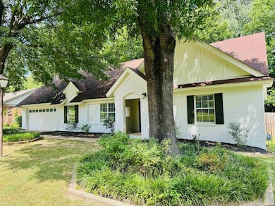 View of front of property with a garage, brick siding, and a shingled roof