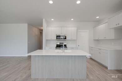 Kitchen featuring appliances with stainless steel finishes, light countertops, a center island with sink, light wood-style floors, and recessed lighting