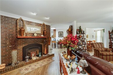 Living room with wood finished floors, a brick fireplace, and crown molding