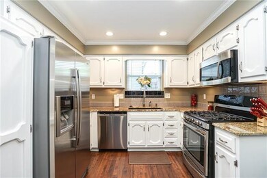 Kitchen features white cabinets, stylish backsplas
