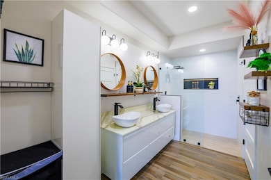 Bathroom with double vanity, walk in shower, recessed lighting, and wood finished floors