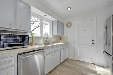 Kitchen featuring light countertops, appliances with stainless steel finishes, tasteful backsplash, and light wood-style floors