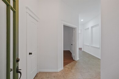 This is a well-lit hallway featuring neutral walls, tile flooring, and multiple doorways leading to other rooms, creating a sense of flow throughout the space.