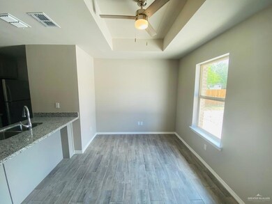 Unfurnished dining area with a raised ceiling, light wood finished floors, and ceiling fan