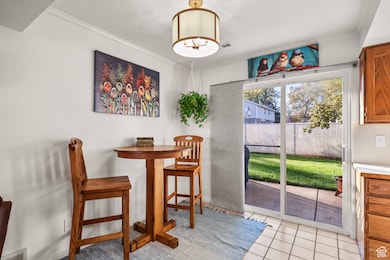 Dining space with light tile patterned flooring, ornamental molding, and a textured ceiling