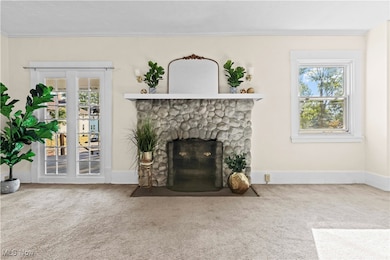 Carpeted living area featuring a stone fireplace