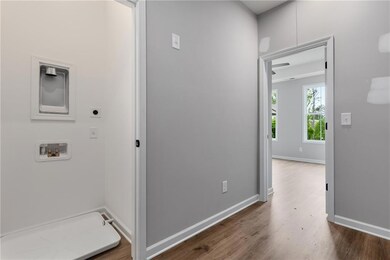 Washroom with electric dryer hookup, wood finished floors, hookup for a washing machine, and baseboards