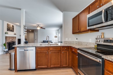 Kitchen with stainless steel appliances, open floor plan, brown cabinets, and a peninsula