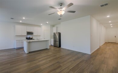 Kitchen with ceiling fan, stainless steel appliances, dark wood-type flooring, a kitchen island with sink, and white cabinetry