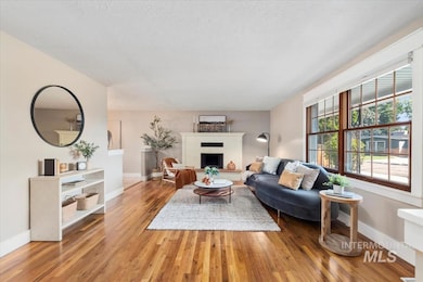 Living room featuring healthy amount of natural light, wood finished floors, a brick fireplace, and a textured ceiling