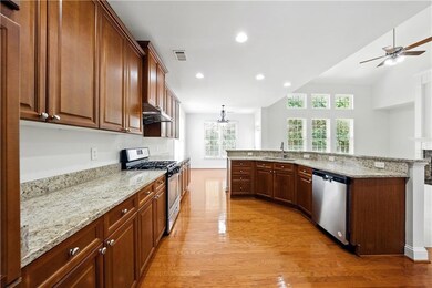 Kitchen with stainless steel appliances, light wood-style floors, ceiling fan, light stone counters, and recessed lighting