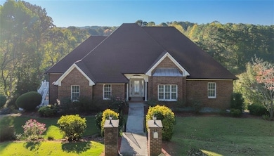 View of front of property with a front lawn, brick siding, and a forest view