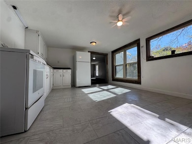 Kitchen featuring white cabinetry, white appliances, a textured ceiling, and dark countertops