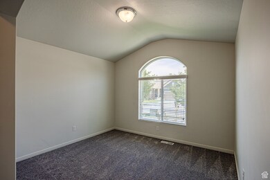 Unfurnished room featuring dark carpet and vaulted ceiling