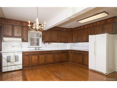 The kitchen has hardwood floors, wood cabinets, under cabinet lighting, chandelier, eat-in area and is open to the family room.