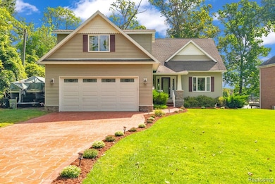 View of front facade with a shingled roof, a front yard, and driveway