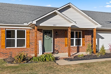 View of front of property featuring brick siding, an attached garage, roof with shingles, a front lawn, and a porch