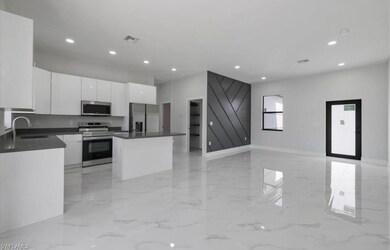 Kitchen featuring stainless steel appliances, light marble finish flooring, dark countertops, white cabinets, and recessed lighting