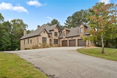French provincial home featuring stone siding, driveway, a garage, a front lawn, and a chimney