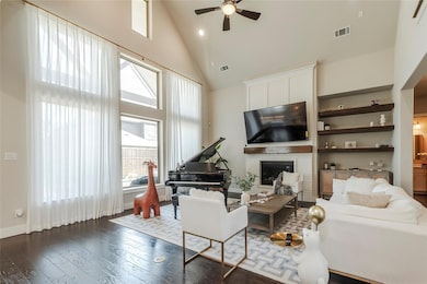 Living room featuring a healthy amount of sunlight, a brick fireplace, high vaulted ceiling, and dark wood-type flooring