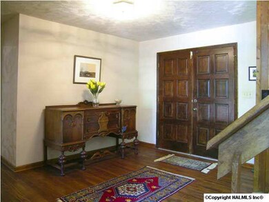 A foyer that makes a statement. Handsome double wood front doors, dark wood flooring and open feeling