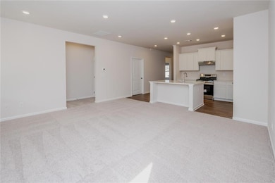 Unfurnished living room with light colored carpet, recessed lighting, baseboards, and a sink