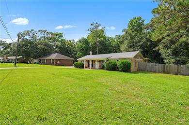 View of front facade featuring a chimney, brick siding, and view of scattered trees