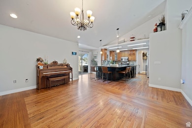 Living area with arched walkways, light wood-style floors, high vaulted ceiling, recessed lighting, and a chandelier