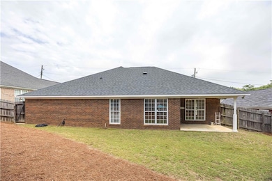 Rear view of house with roof with shingles, a patio, and brick siding