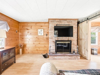 Living area featuring wood walls, wood finished floors, a barn door, and a fireplace