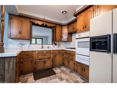 The kitchen has tile countertops, a gas cooktop, b