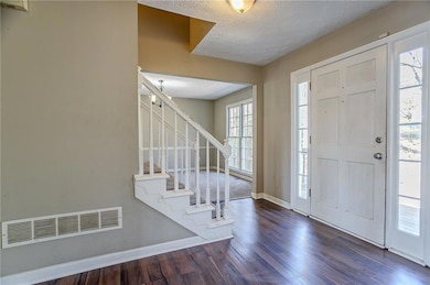 Entryway with a textured ceiling, dark wood-type f