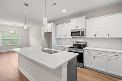 Kitchen featuring appliances with stainless steel finishes, decorative backsplash, white cabinetry, and recessed lighting
