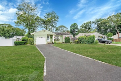 View of front facade featuring driveway, a garage, and a chimney