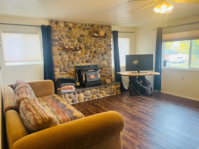 Living area featuring a wood stove, dark wood-style flooring, ceiling fan, and a textured ceiling